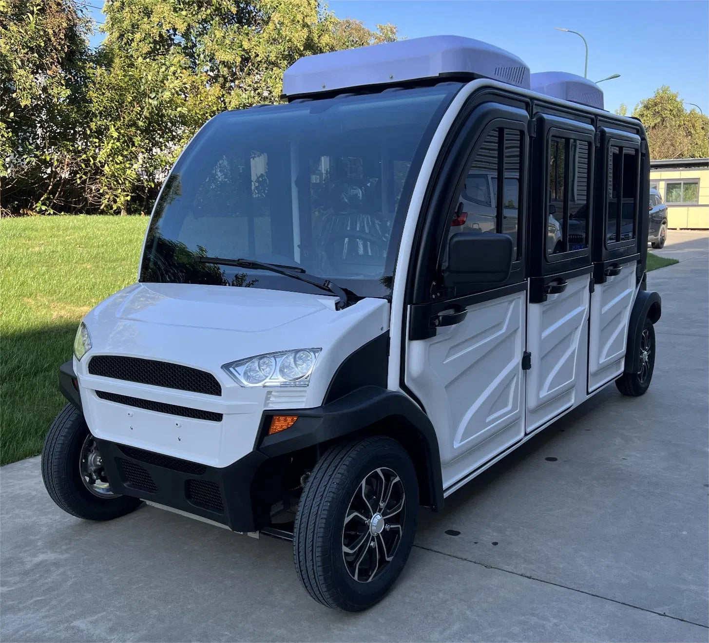White and black golf cart on a concrete surface with trees in the background