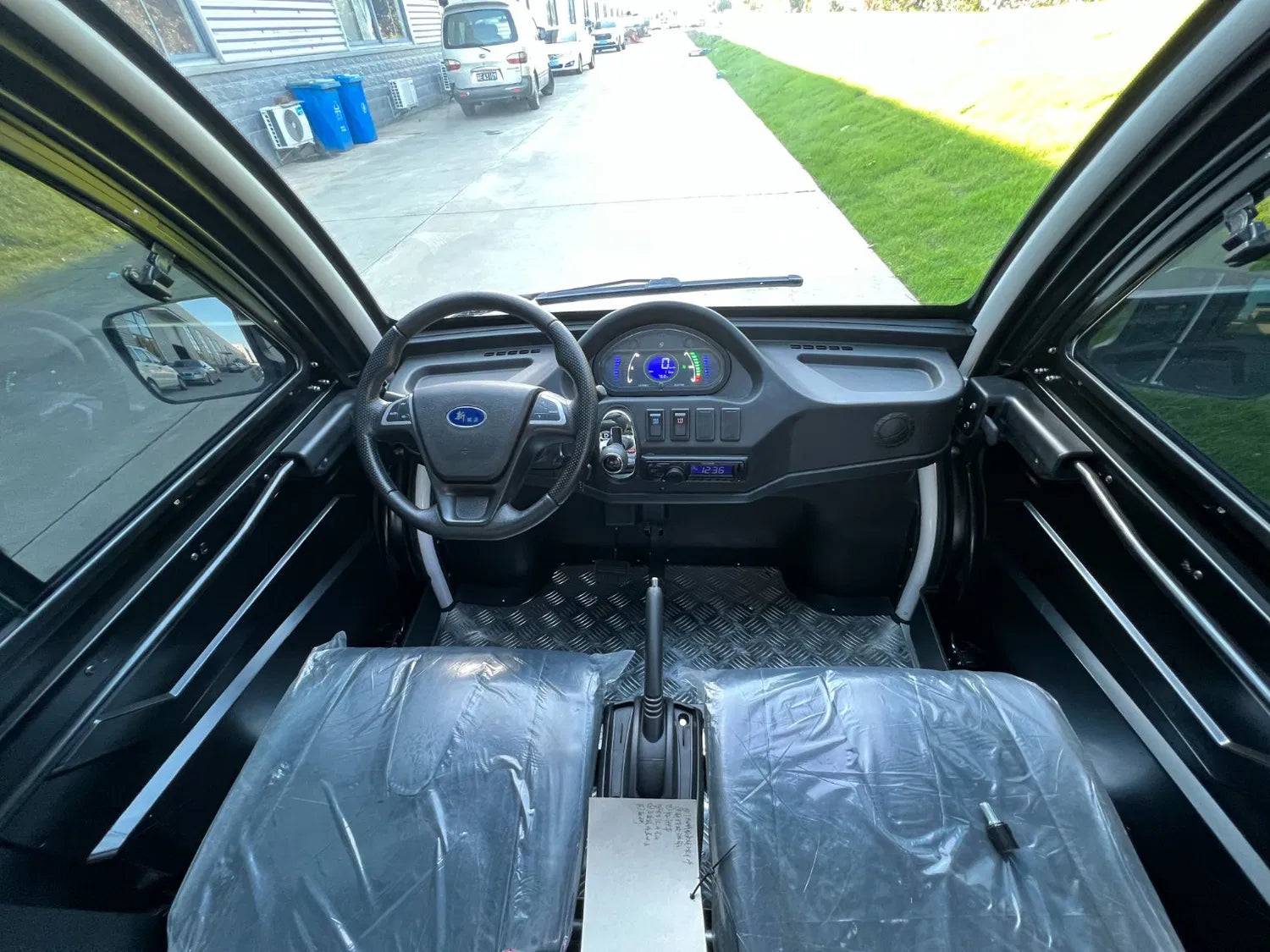 Interior of a vehicle with steering wheel and dashboard, showing a clear view of the road ahead.