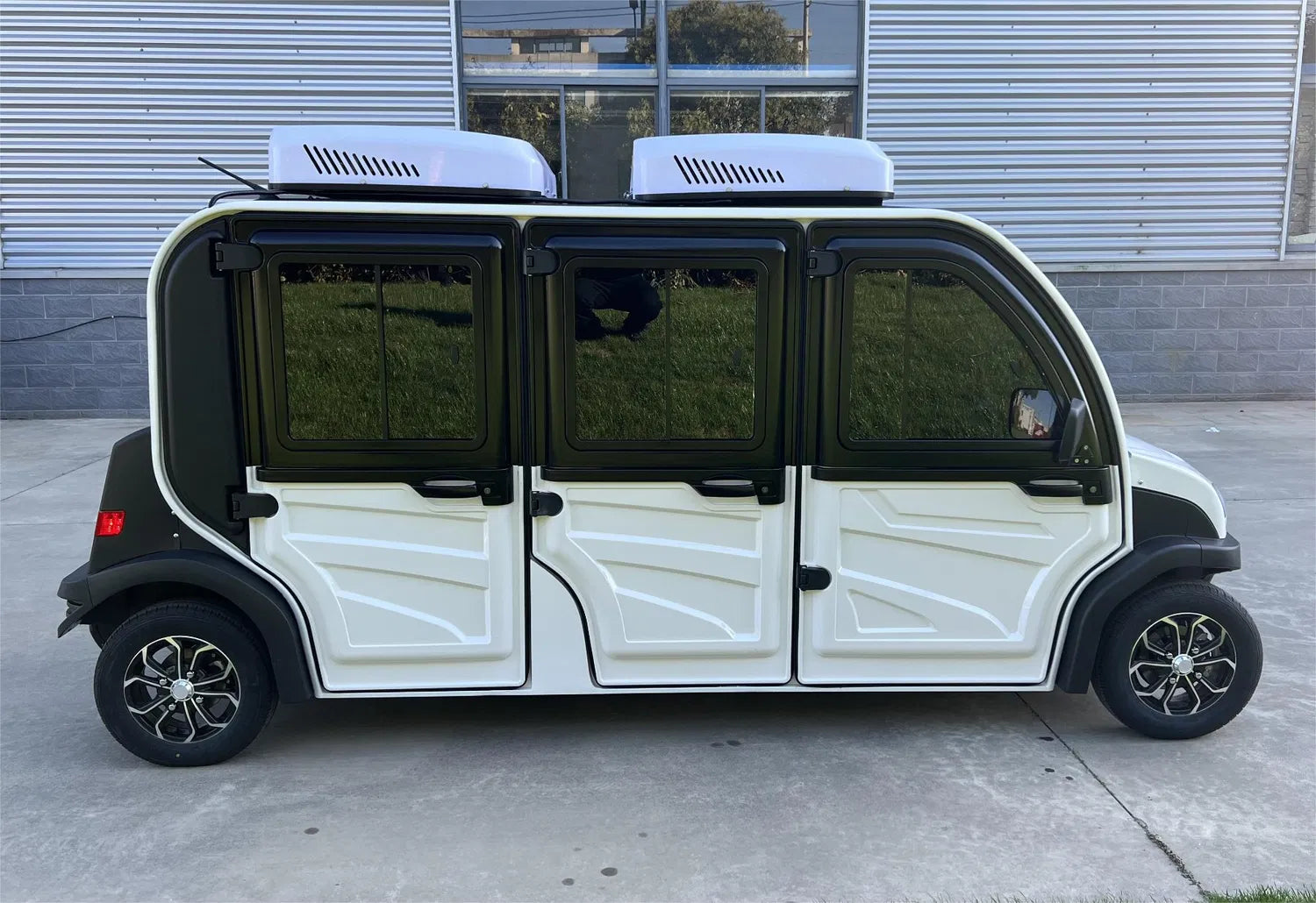 Small electric vehicle with solar panels on roof parked on pavement.