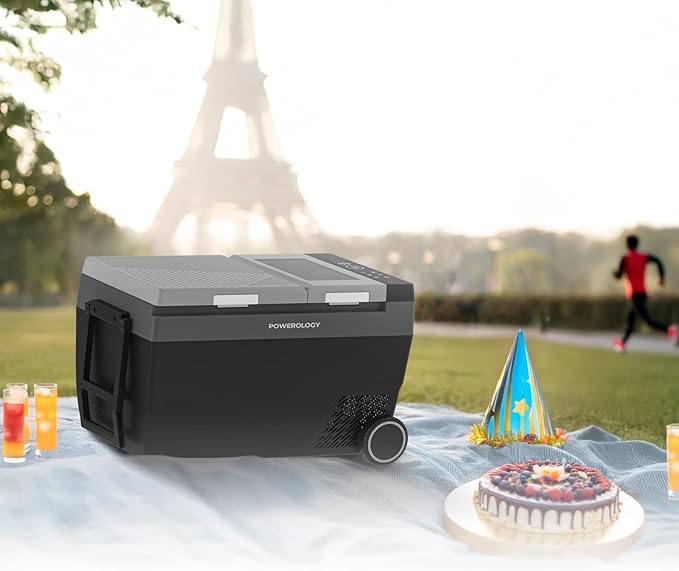 Portable cooler with Powerology branding on a picnic setup with a cake and drinks, blurred Eiffel Tower in the background.