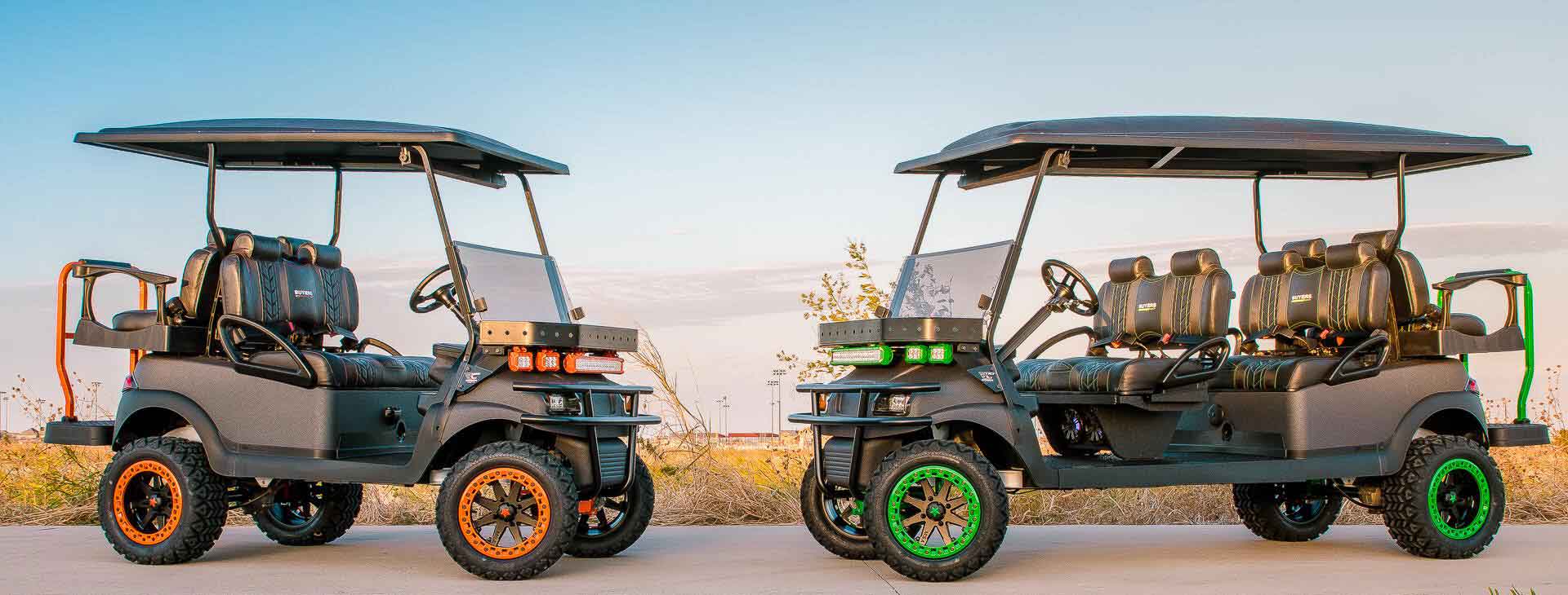 Two golf carts, one with orange wheels and the other with green wheels, on a road.