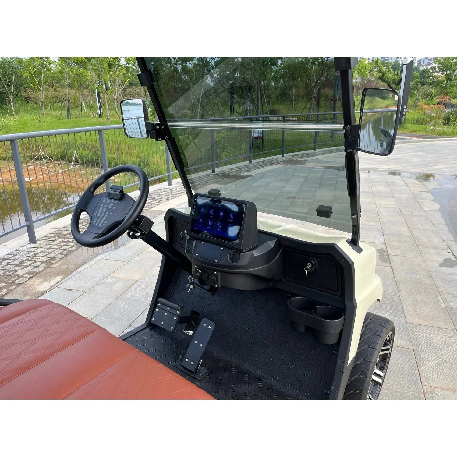 Closeup of the golf cart's dashboard featuring a 12-inch screen, steering wheel, and control pedals.