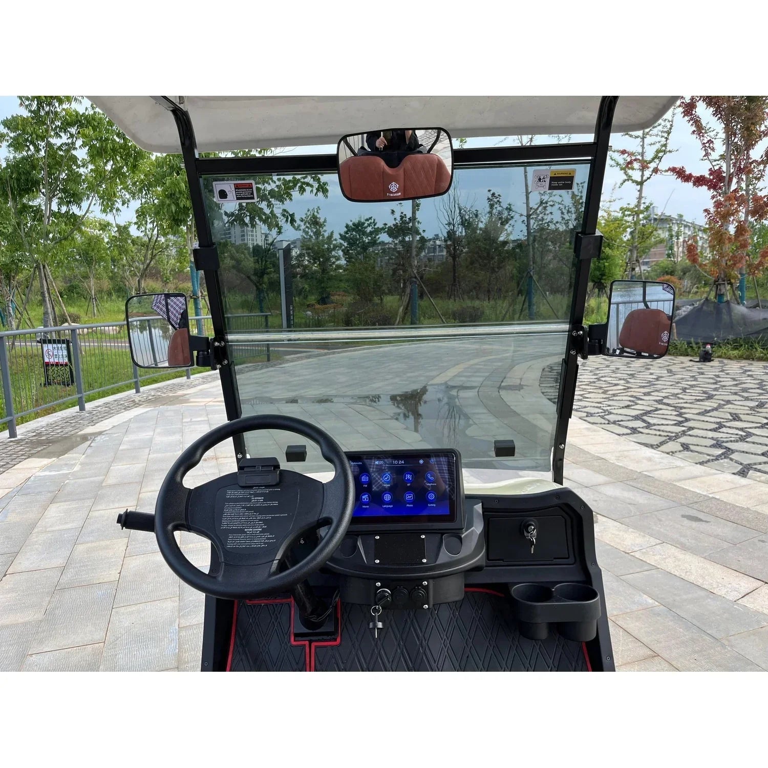 A close-up view of the golf cart's dashboard featuring a black steering wheel and a 12-inch touchscreen display showing app icons.