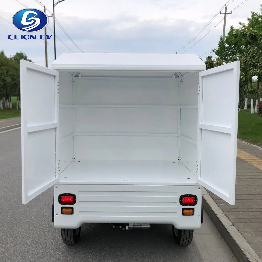 ocean cartz rear view of a white enclosed electric delivery vehicle with both back doors wide open, showcasing the empty rear cargo box. This shot highlights the large internal storage capacity and the two fixed interior shelves of the electric utility truck. The last-mile delivery NEV is parked on an asphalt road with a sidewalk and trees in the background.