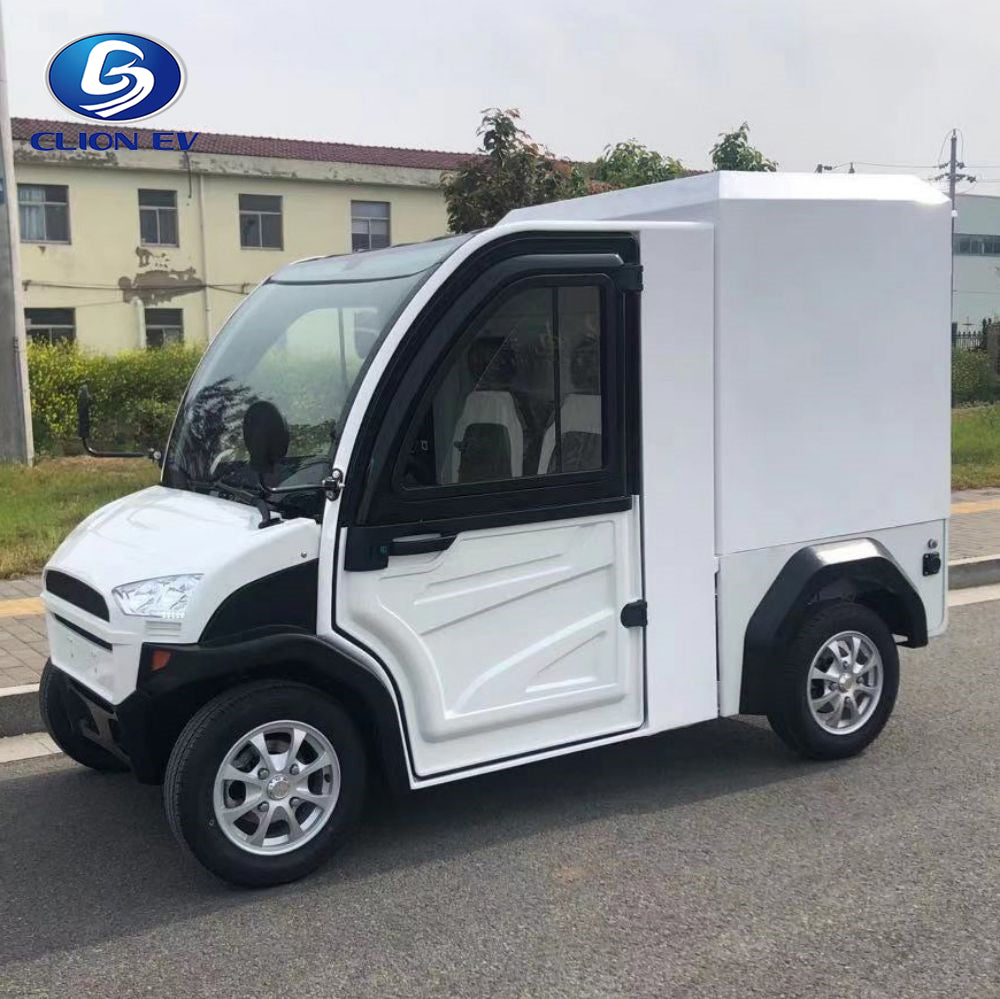 ocean cartz side view of a white enclosed electric delivery vehicle with a large rear cargo box, parked on an asphalt road. This two-seater commercial NEV or electric utility truck features black accents around the windows and fenders, a modern front end, and small, multispoke silver alloy wheels. The vehicle is designed for secure last-mile delivery and efficient urban logistics in a commercial or residential setting.