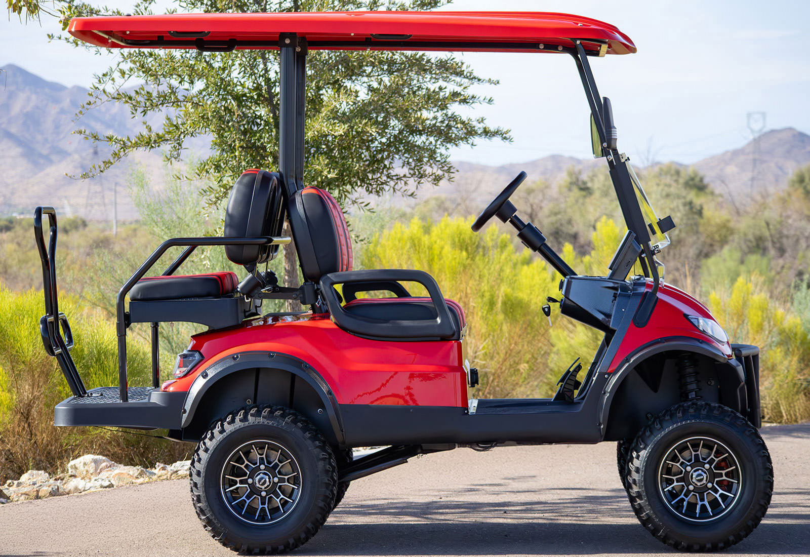 Red golf cart on a road with greenery and mountains in the background