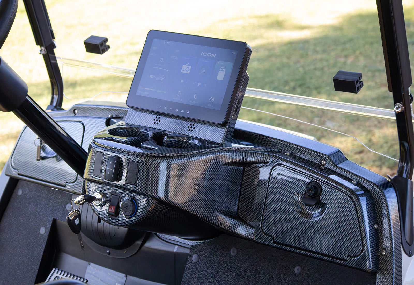 Close-up of a vehicle's dashboard with a touchscreen display and carbon fiber finish.