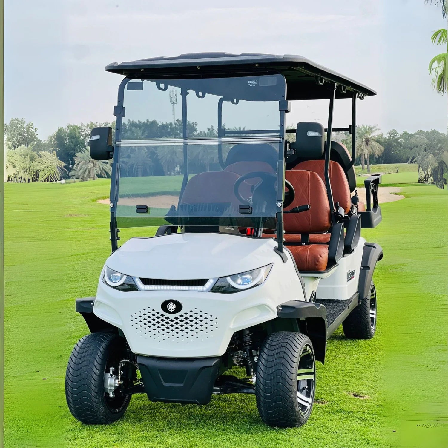 White golf cart on a golf course with trees in the background