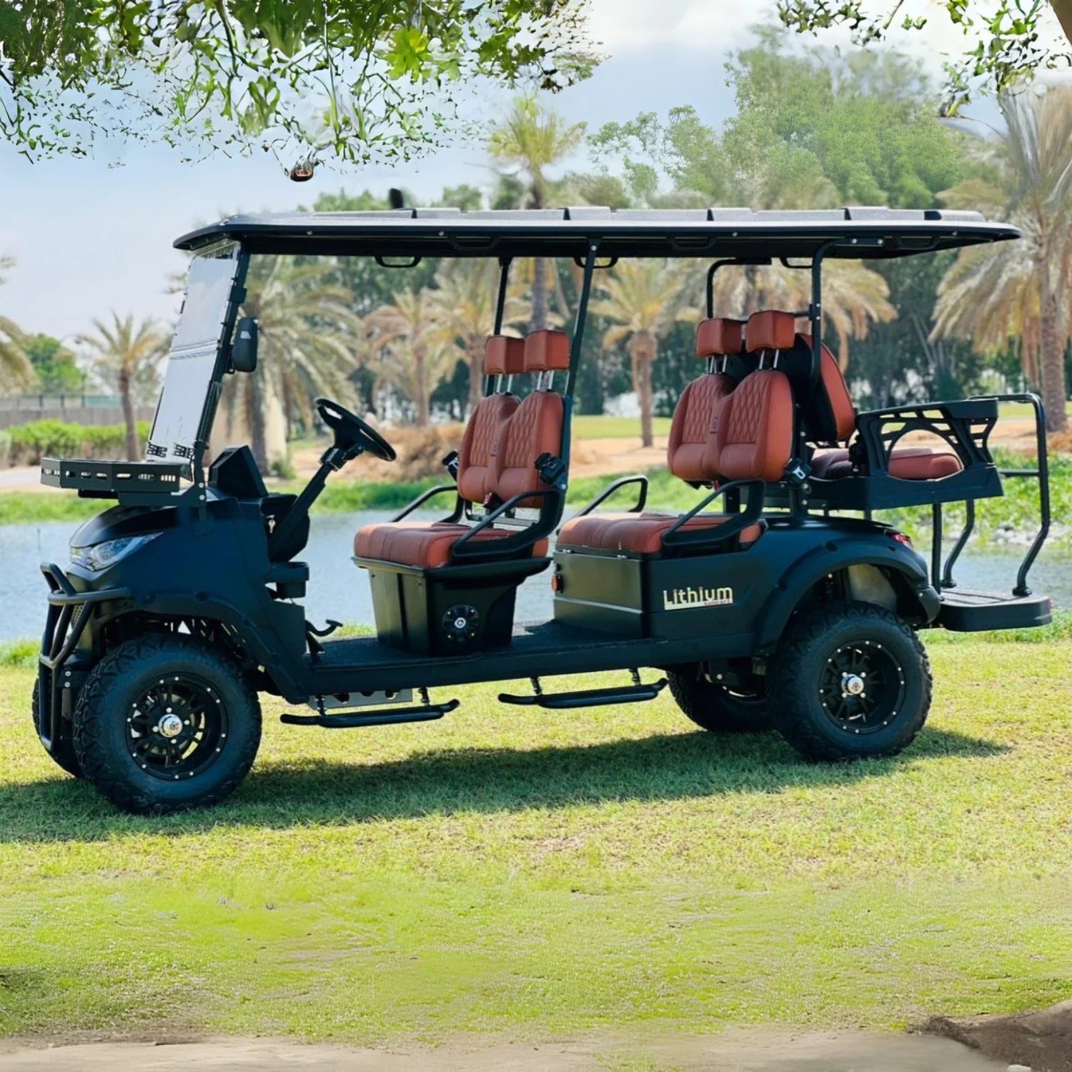 Electric golf cart with red seats on a grassy area with trees in the background